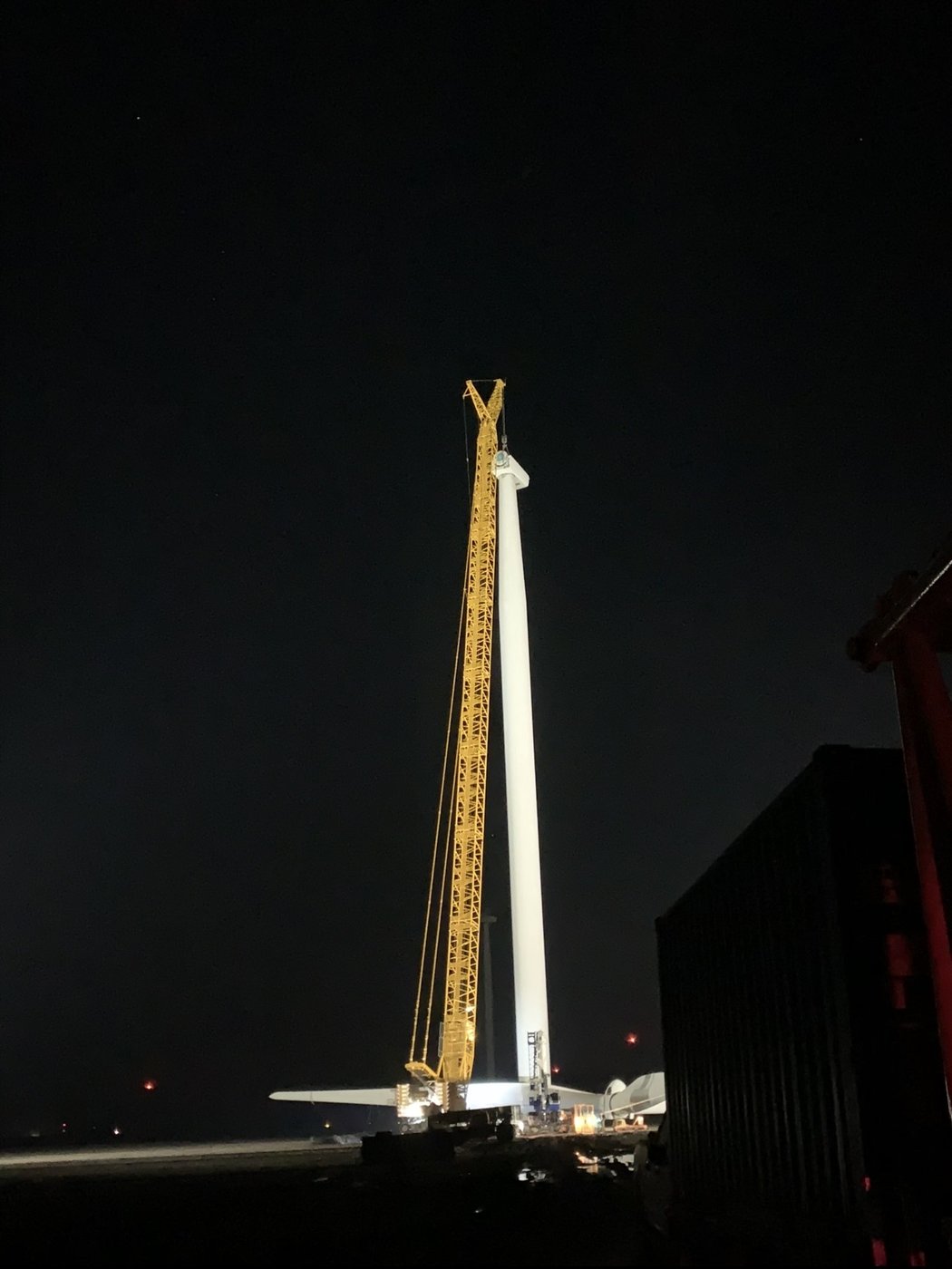 Lattice boom crane lifting at night on a wind project