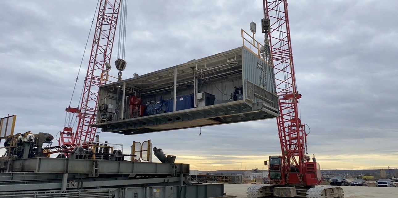 Two crawler cranes tandem lifting a rig component during a rig move